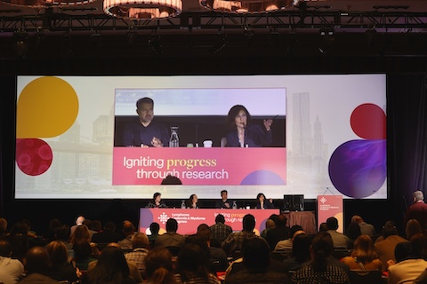 Conference presenters sitting in front of a big screen